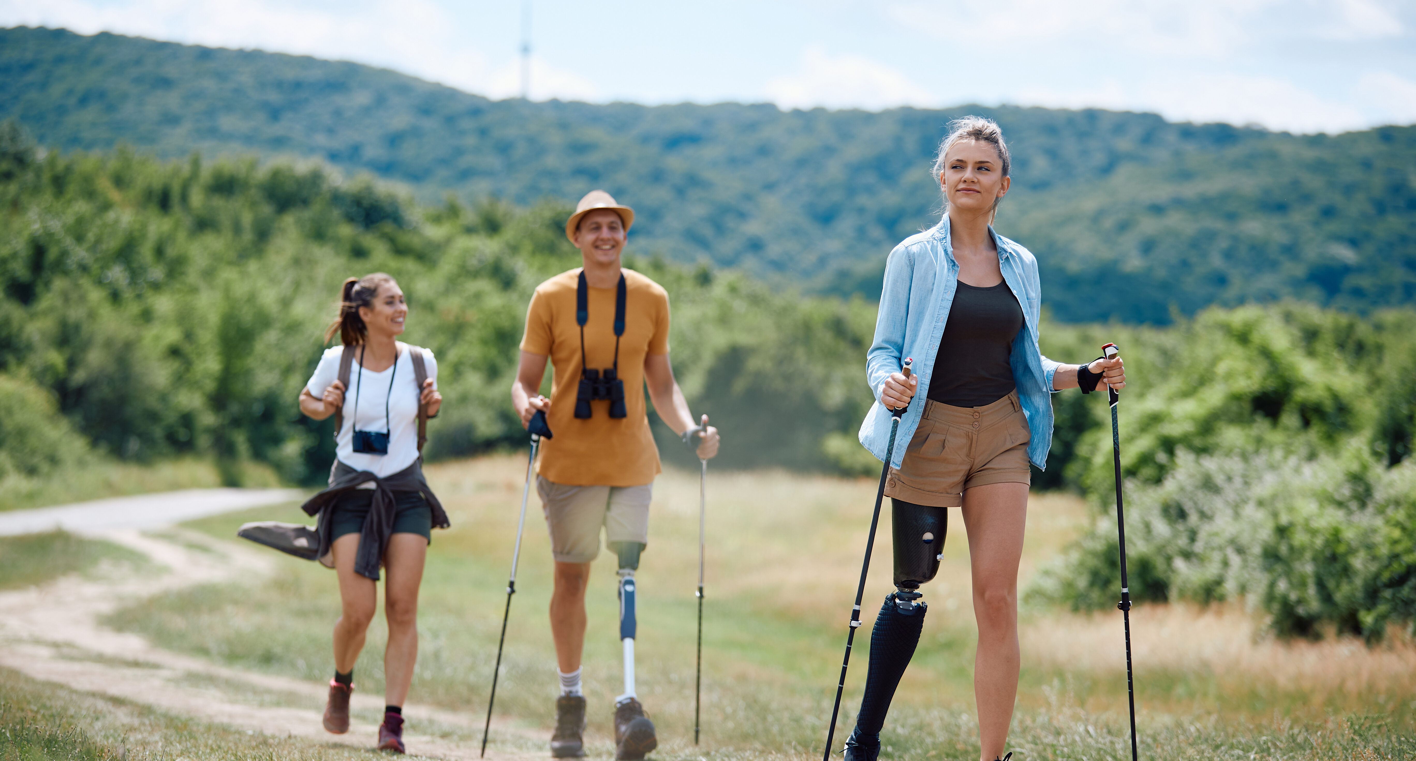 Young woman with leg disability uses poles while hiking with friends in nature.