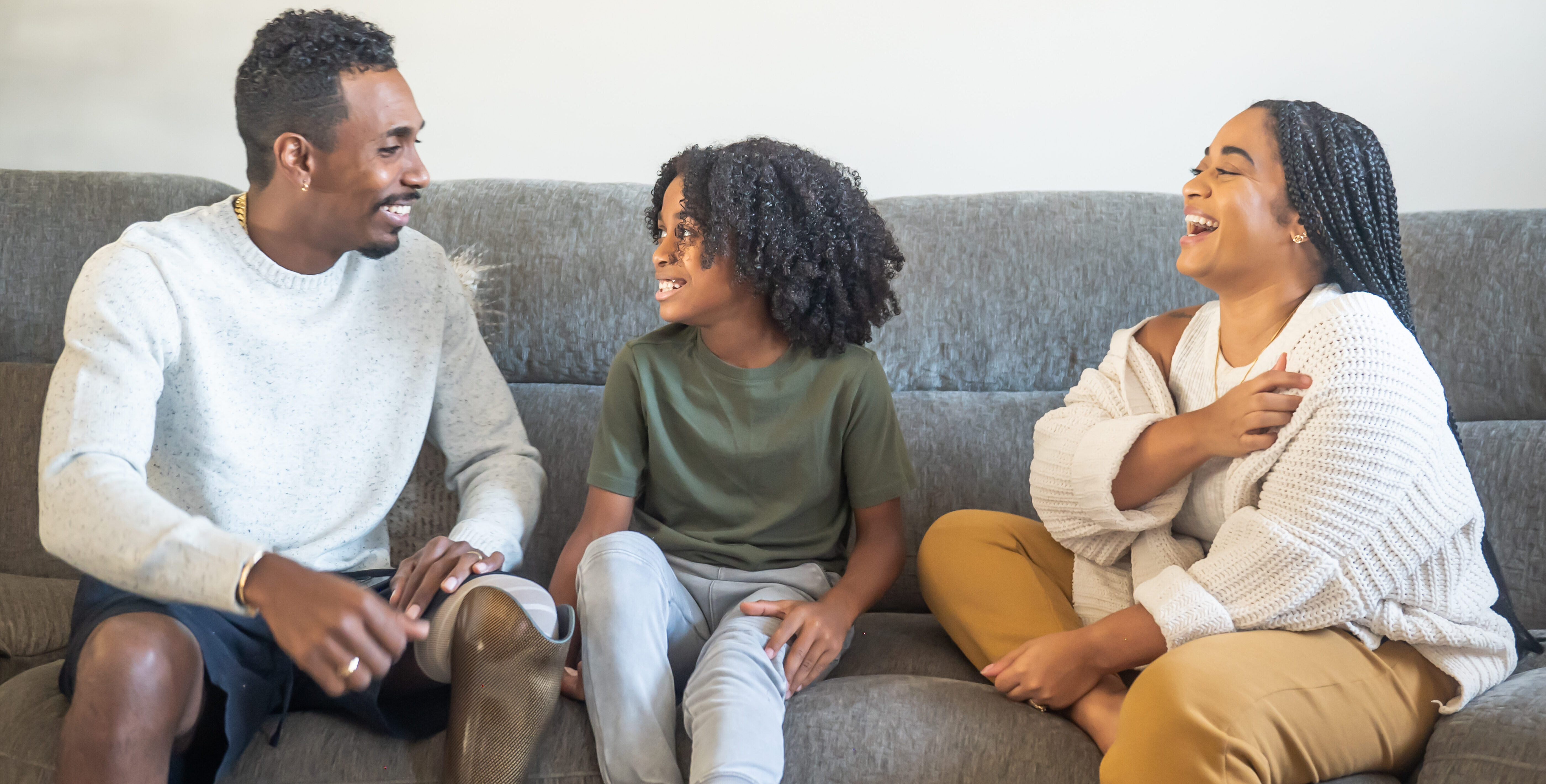 Boy with mother and father with prosthetic leg sitting on sofa